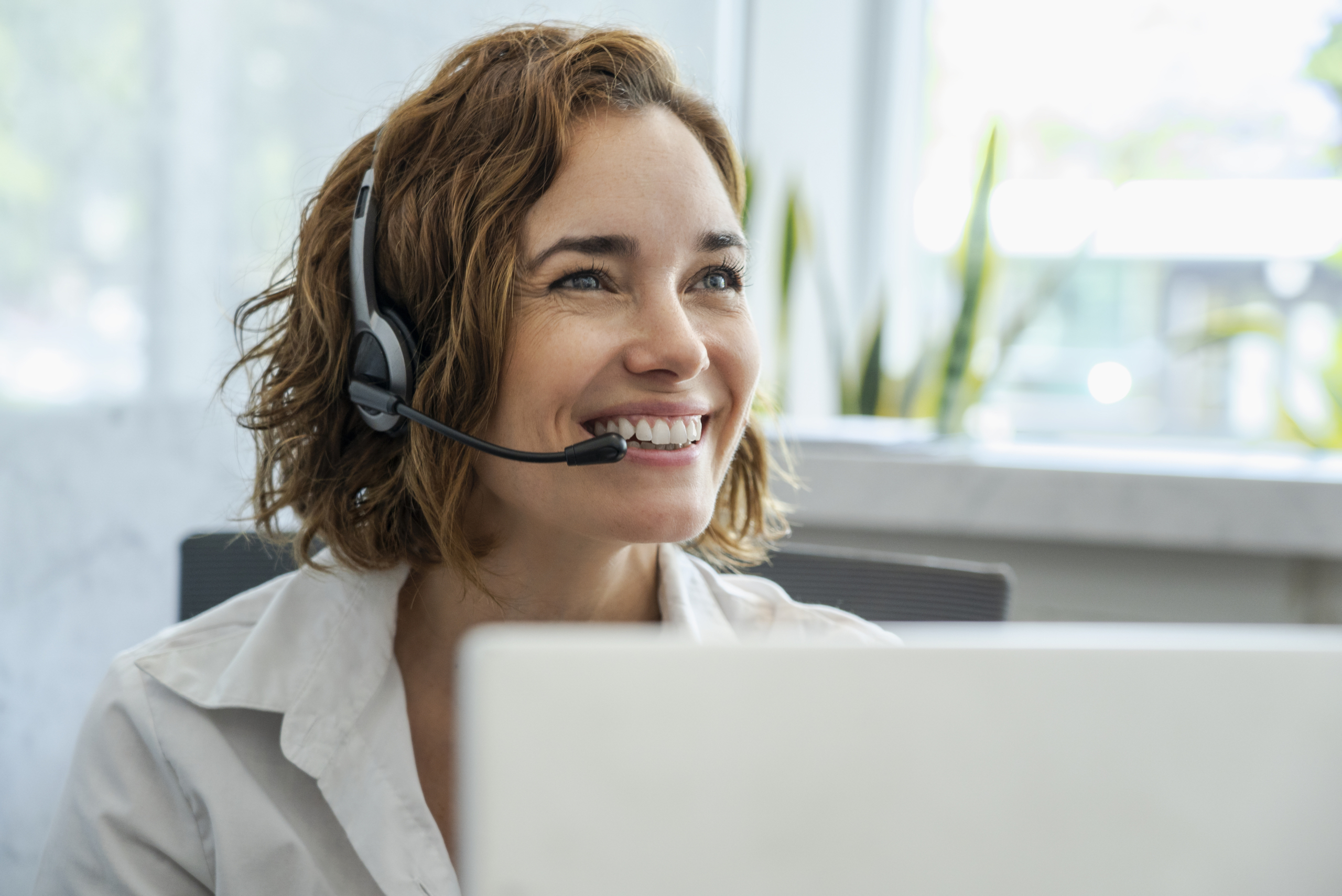Customer service representative wearing headset in the office Close-up of smiling mature female customer service representative wearing headset in office