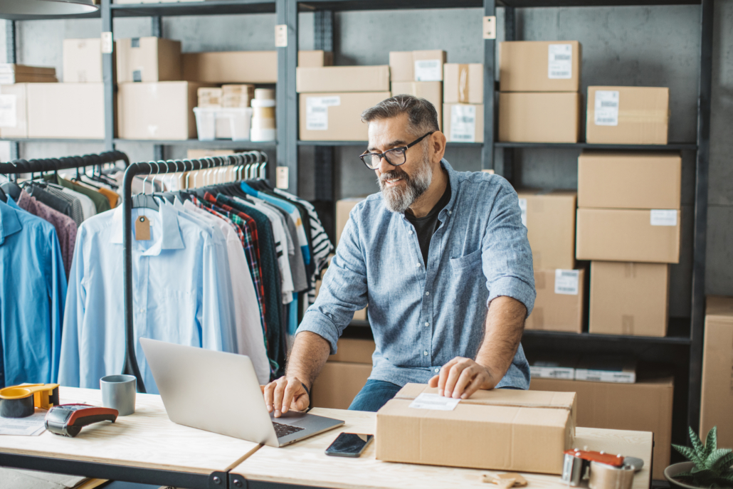 Mature man running online store Mature men at online shop. He is owner of small online shop. Receiving orders and packing boxes for delivery.