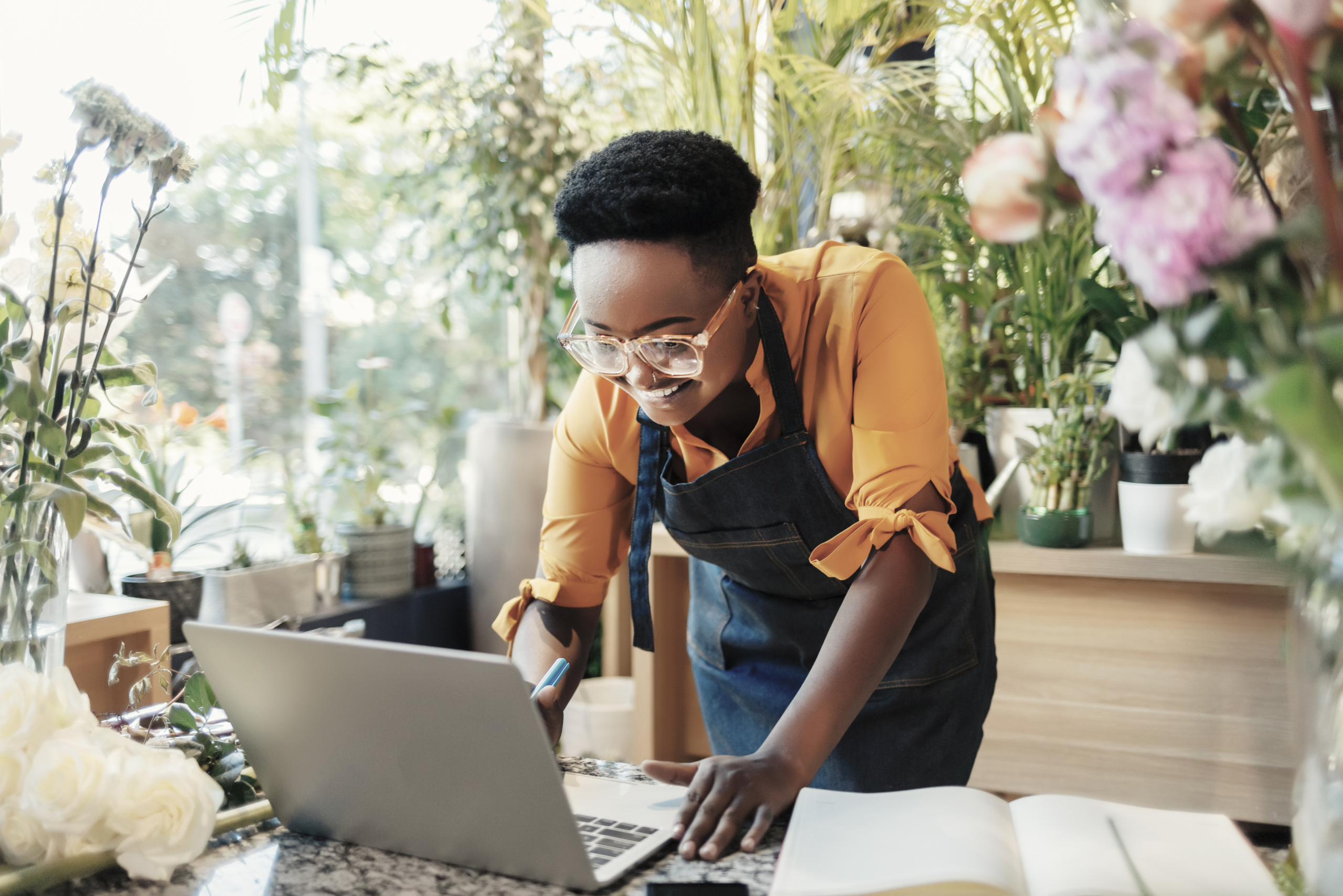 You don’t need an office to grow your success African American Female Florist Using Laptop at Counter in Flower Shop