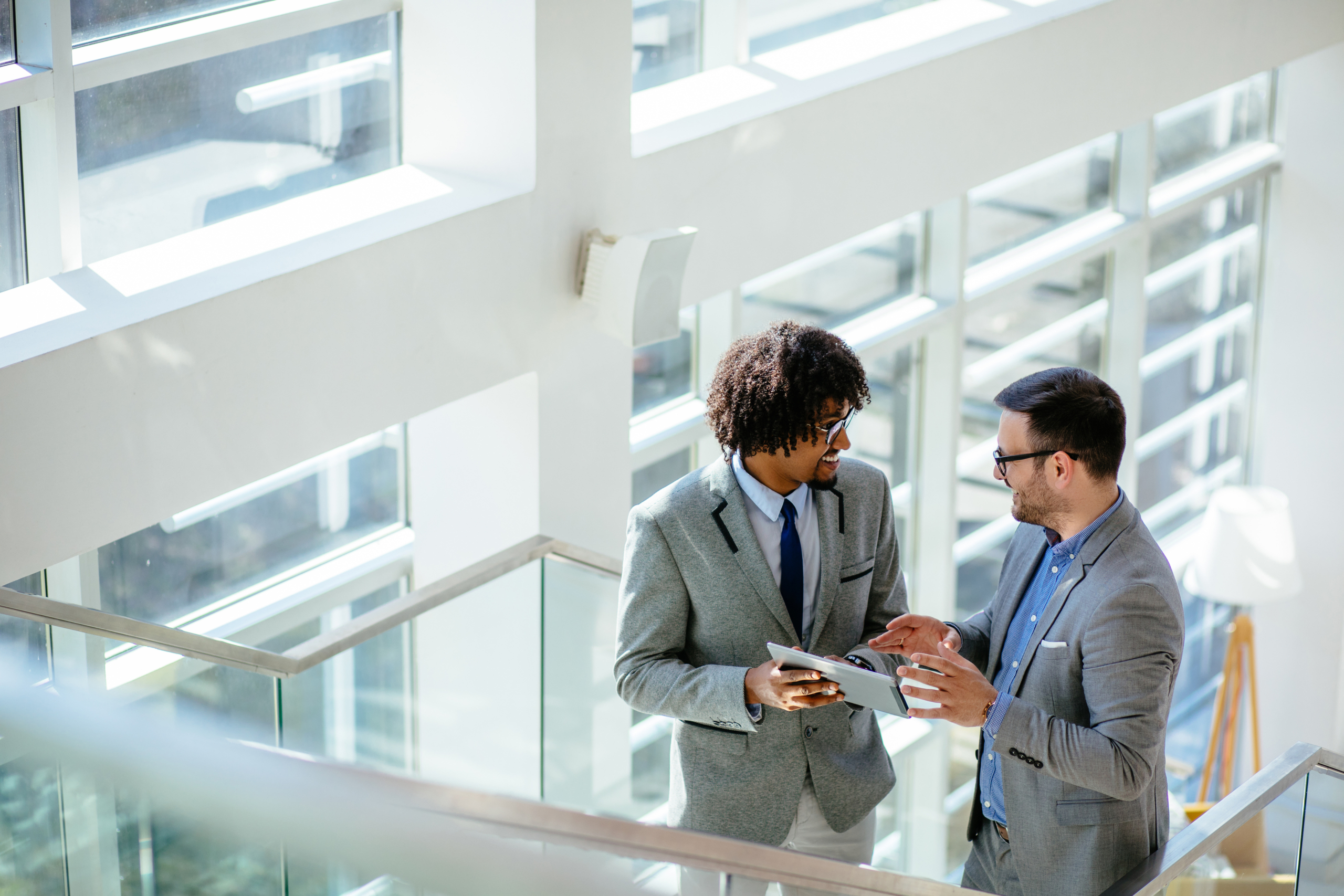 Two businessmen standing on staircase while using digital tablet Two businessmen standing on staircase while using digital tablet